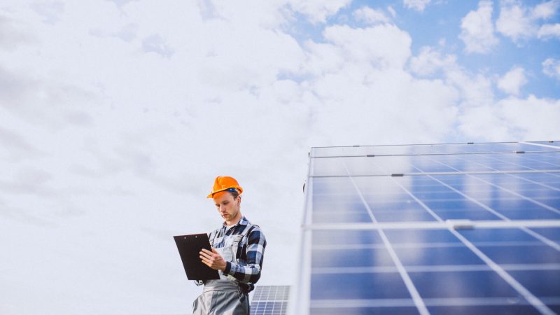 Man worker in the firld by the solar panels