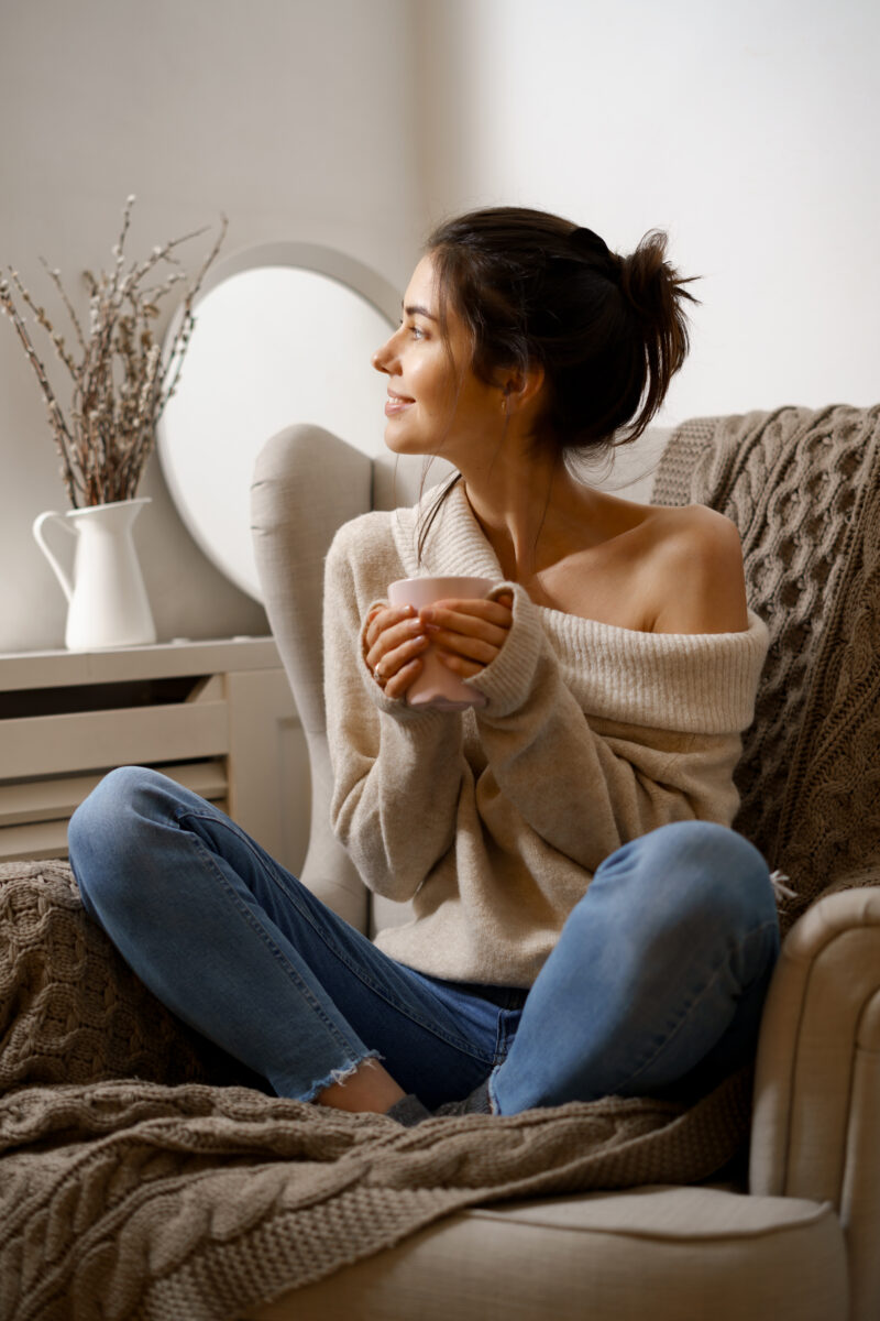Dona de perfil sentada al sofá amb una tassa de café